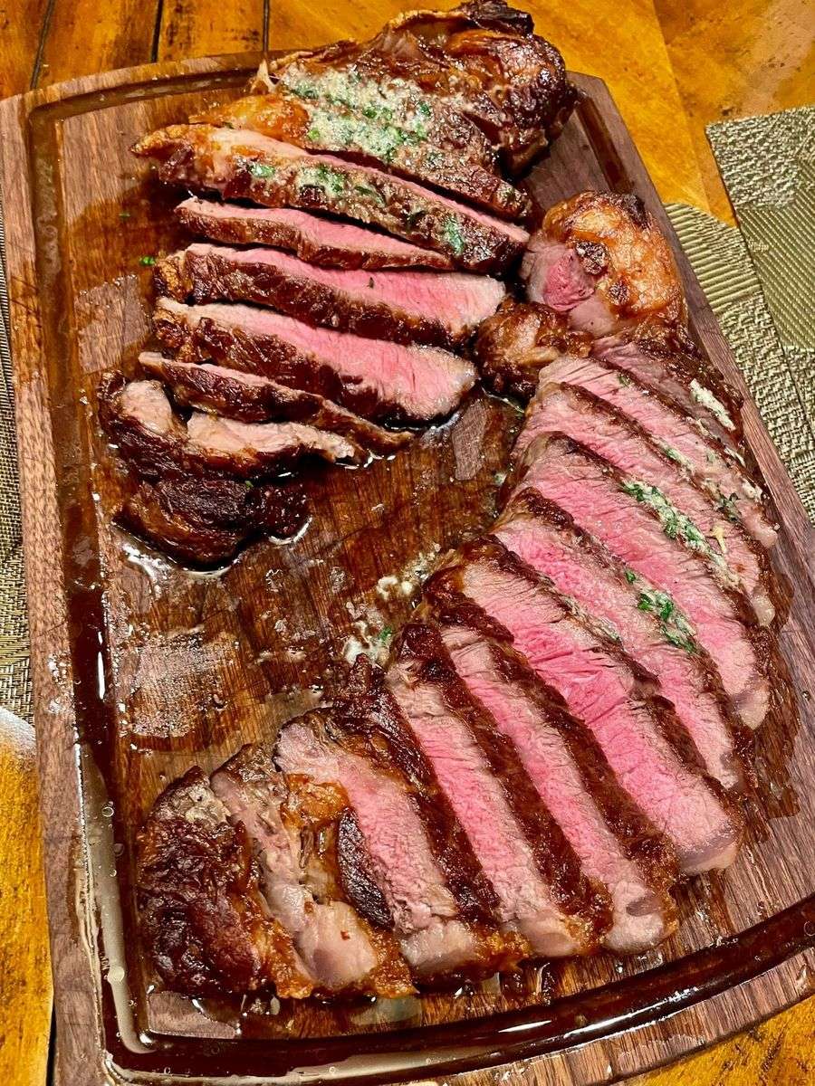 Sliced herb-buttered steaks on a wooden cutting board