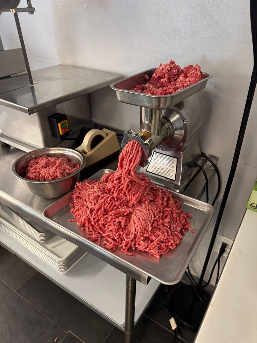 Butcher grinding fresh beef into a tray